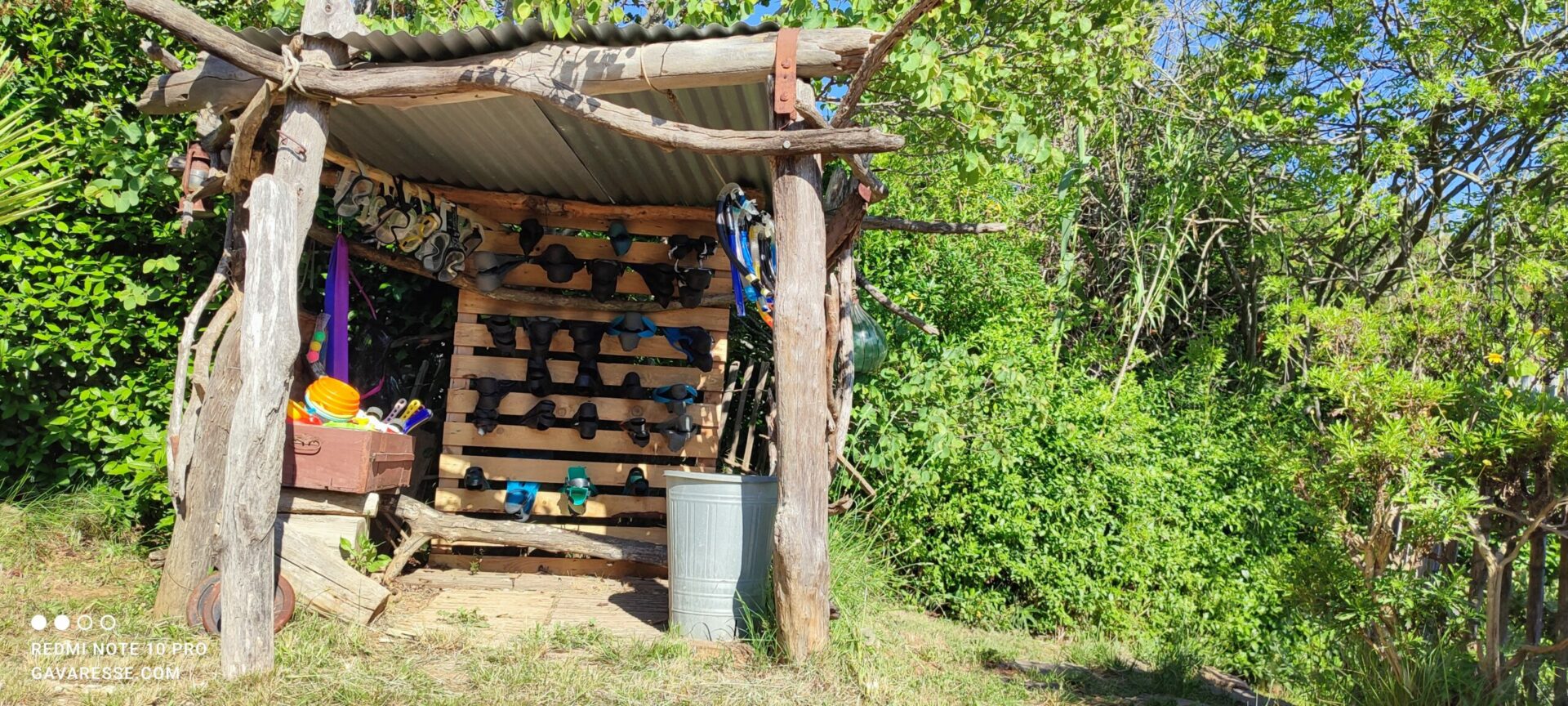 Vue d'un "bar à palmes" en bois avec masques, tubas et palmes de différentes tailles, à disposition des hôtes pour le snorkeling et la découverte des fonds marins au Mas de la Gavaresse.