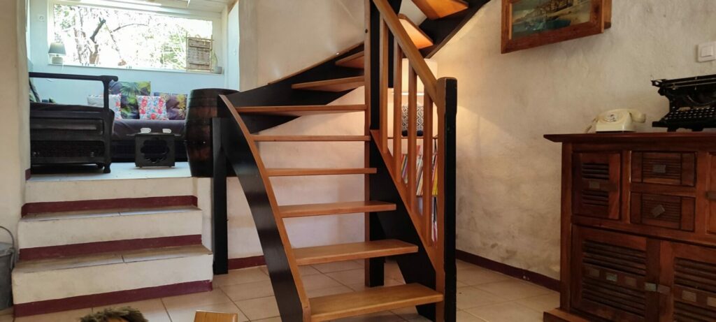 Grand escalier en bois menant aux chambres à l'étage du gîte La Fenière, avec rambarde en fer forgé, Le Pradet.