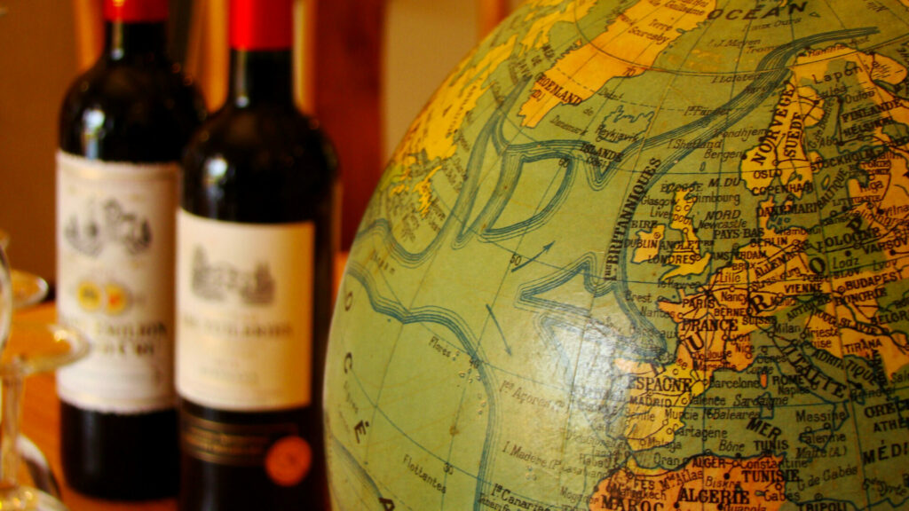 Globe terrestre ancien et deux bouteilles de vin en arrière-plan, suggérant une ambiance de voyage et de découverte.