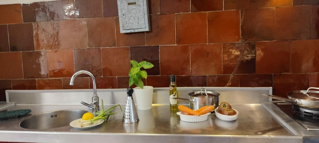 Bouteille d'huile d'olive et pot de basilic sur le plan de travail en pierre de la cuisine de La Fenière, Le Pradet.