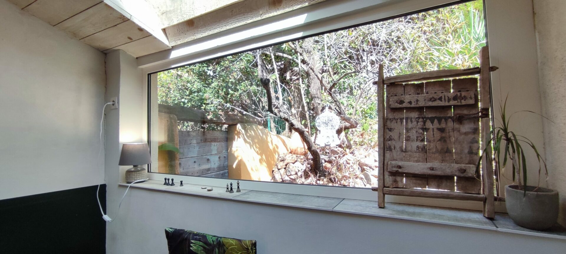 Grande imposte en bois dans le salon du gîte La Fenière, offrant une vue encadrée sur le jardin, Le Pradet.