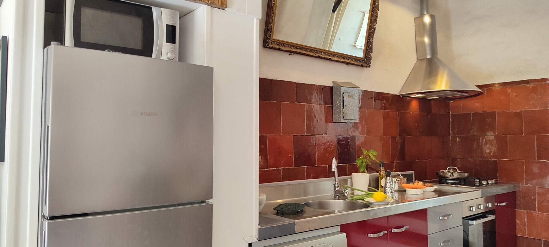 Réfrigérateur-congélateur moderne et placard en bois dans la cuisine du gîte La Fenière, avec volet ancien au-dessus, Le Pradet.