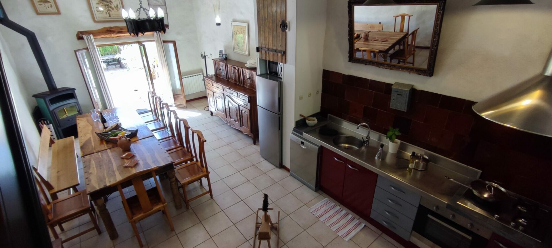 Vue plongeante sur le grand séjour du gîte La Fenière depuis la cuisine, avec grande table en bois, poêle à bois, Le Pradet.