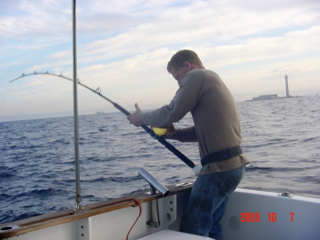 Pêcheur sur un rocher au lever du soleil, lançant sa ligne dans la mer Méditerranée, côte varoise.