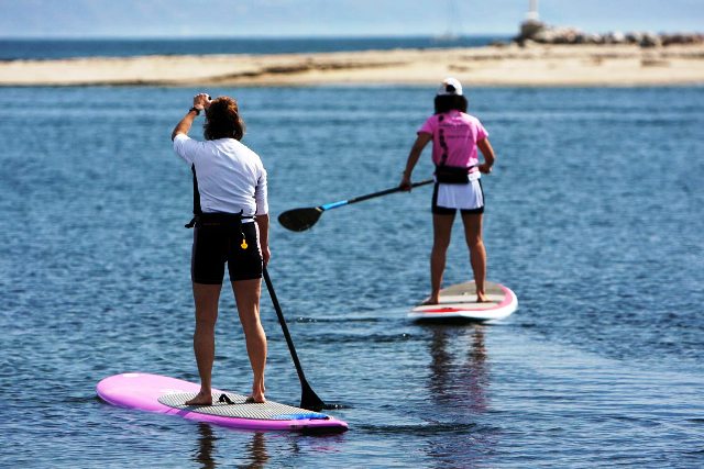 Personne debout sur un paddle board, ramant sur une mer calme au coucher du soleil, activité aquatique relaxante, Le Pradet.
