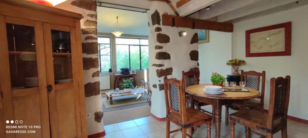 Grand séjour salon du gîte L'Orangeraie avec murs en pierres, coin repas, et vue sur le salon lumineux, Le Pradet.
