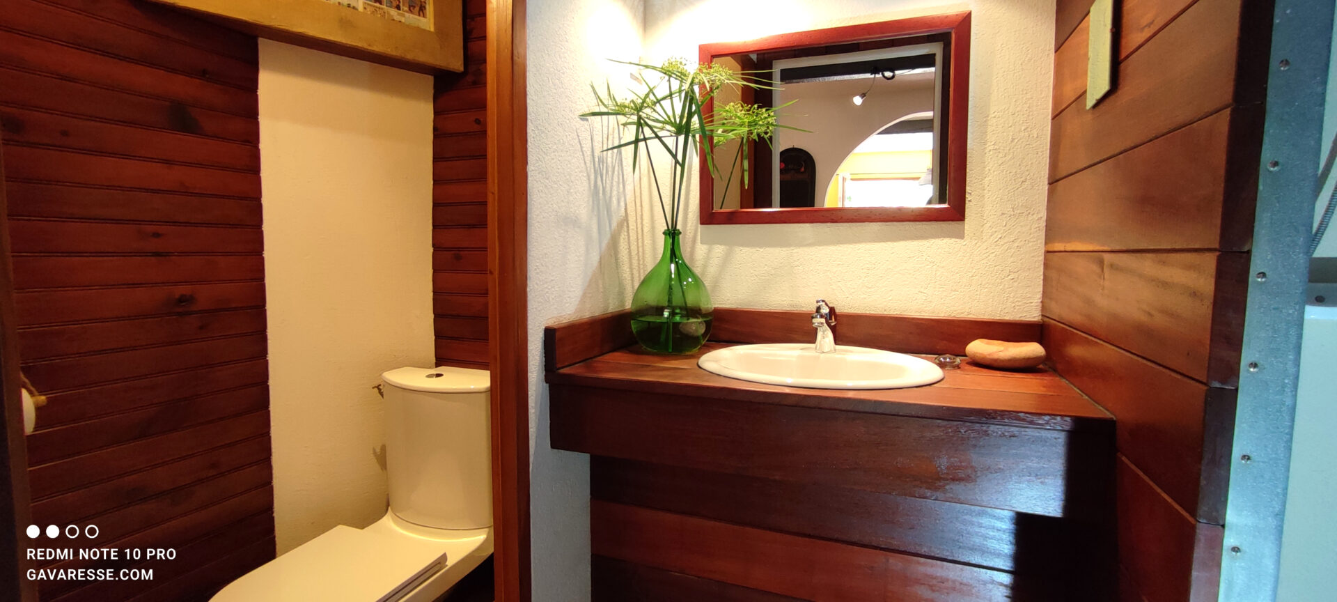 Salle de bain du gîte Le Pénéquet avec vasque en faïence, plan en bois exotique, miroir et toilettes, ambiance cosy, Le Pradet.