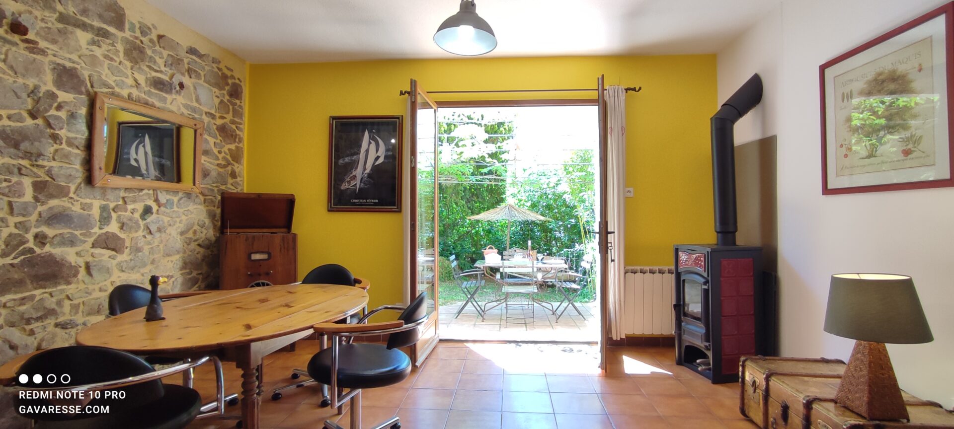 Vue de la cuisine vers le séjour avec poêle à bois et l'accès à la terrasse du gîte Le Pénéquet, Le Pradet.