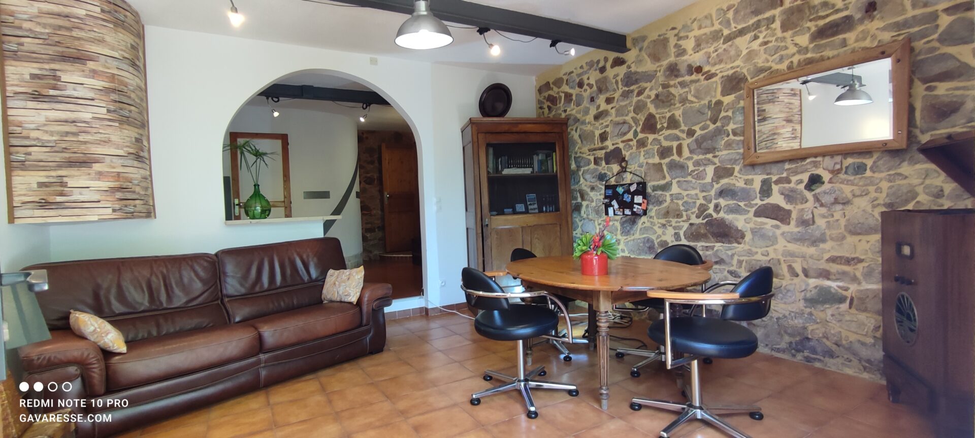 Enfilade séjour et coin repas du gîte Le Pénéquet, murs en pierres apparentes, sol en terre cuite, Mas de la Gavaresse.