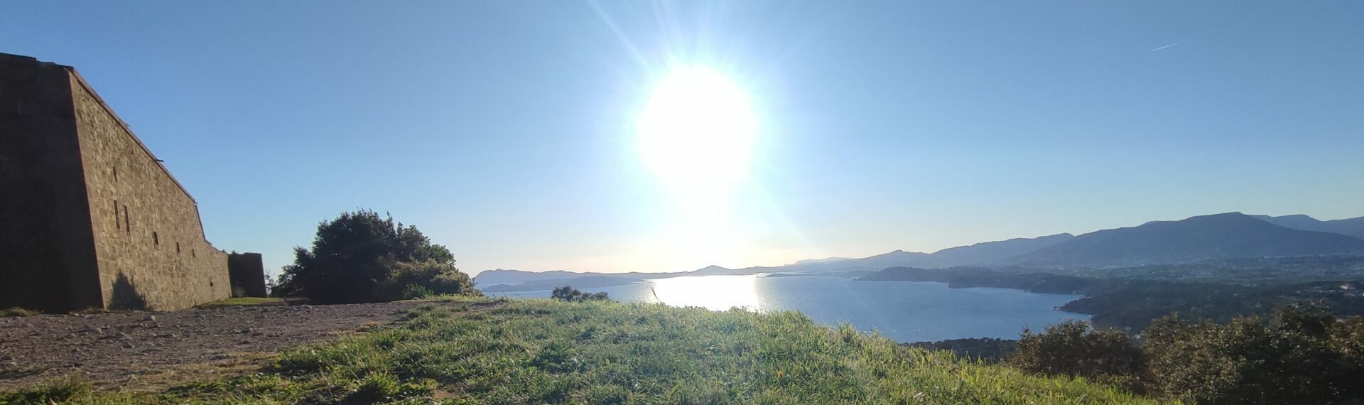 Vue panoramique depuis le sommet de la Colle Noire, montrant un pan du fortin de la Gavaresse, la garrigue, la baie de Toulon et Le Pradet sous un ciel bleu éclatant.