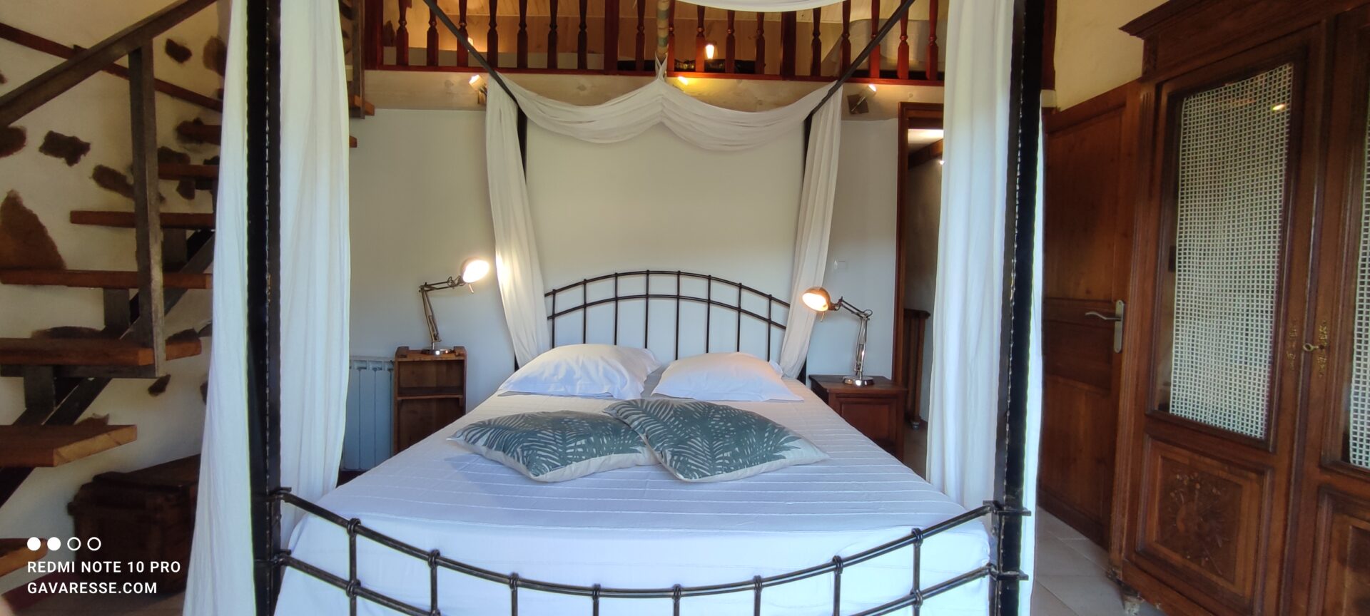 Lit à baldaquin avec rideaux ouverts et décoration florale dans la chambre parentale de La Fenière, ambiance douce, Le Pradet.