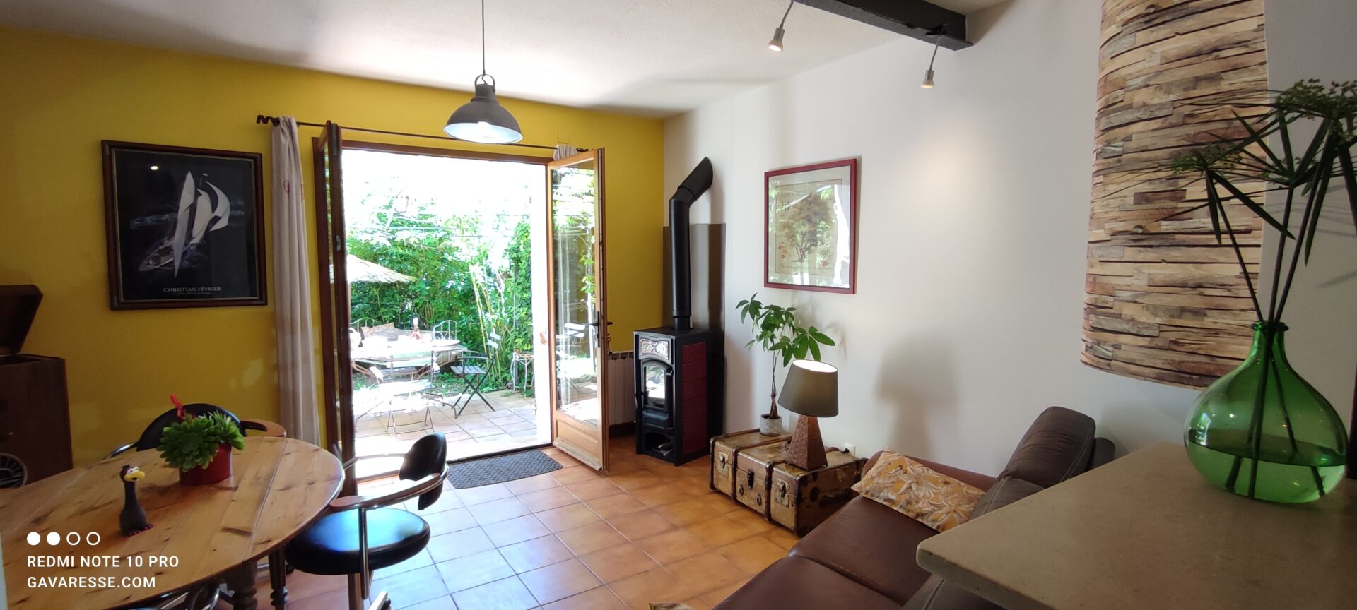 Séjour du gîte Le Pénéquet avec poêle à bois, canapé, et vue sur la terrasse extérieure, Le Pradet.