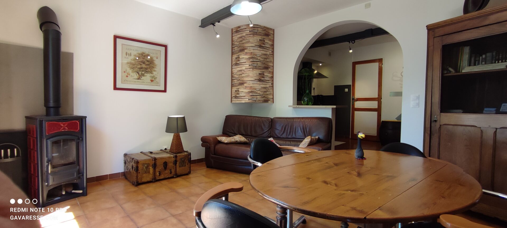 Séjour du gîte Le Pénéquet avec poêle à bois, canapé cuir et vue sur la cuisine voûtée, Mas de la Gavaresse.