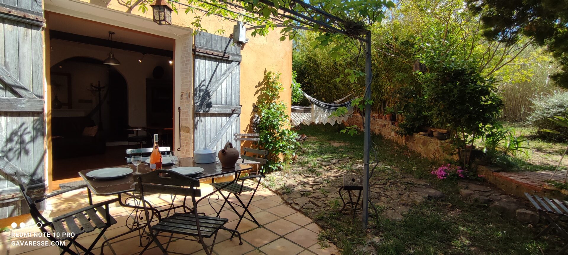 Terrasse privative du gîte Le Pénéquet avec table et chaises, vue sur le jardin et les hamacs, Le Pradet.